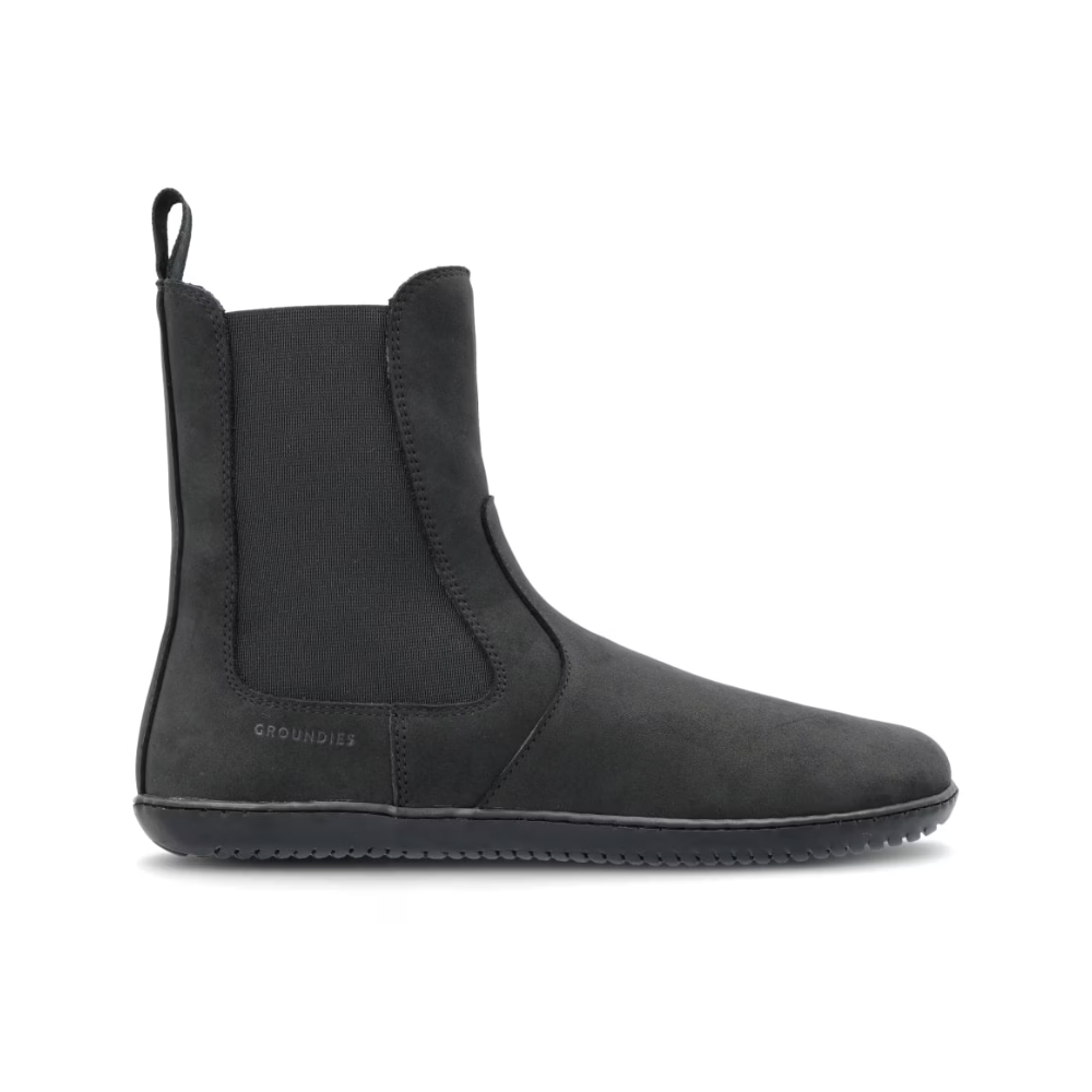 Bota Chelsea negra minimalista de perfil, con panel elástico y tirador trasero.