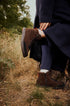 Person wearing brown lace-up ankle boots on a path through grass.