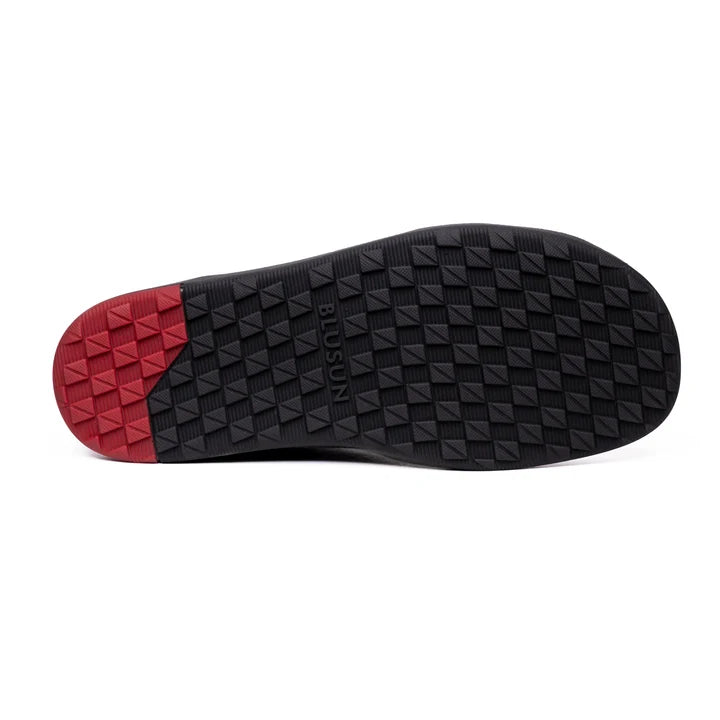 Black ankle boot sole with a geometric pattern and a red section at the heel.