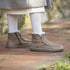 Botines beige con forro de lana, llevados con medias claras sobre un camino.